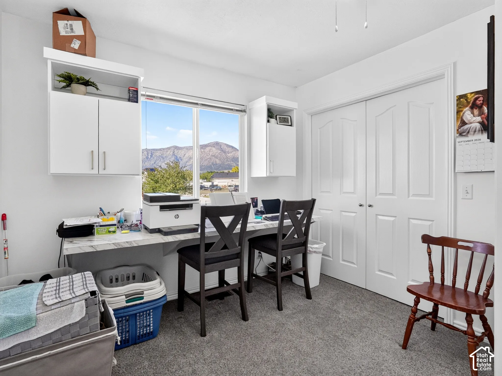 Built-in desk with a white marble-finish countertop, dual upper white cabinetry, and carpet flooring