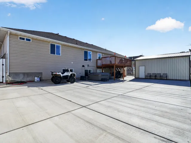Expansive concrete patio with a hot tub and a separate detached shed