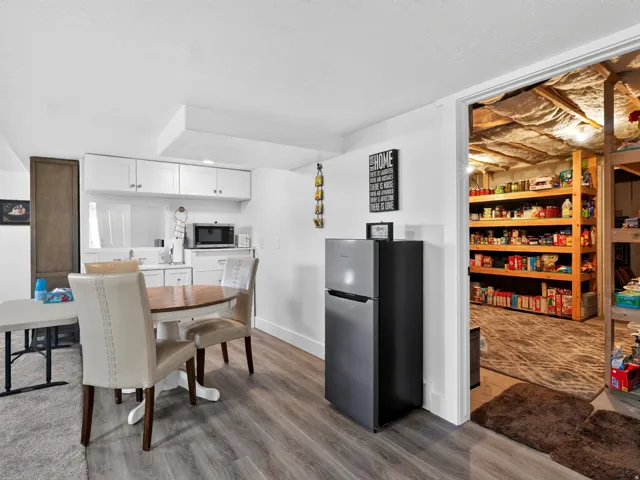 Kitchenette featuring white cabinetry, a built-in microwave, and wood-finish flooring