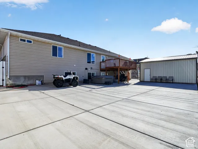 Expansive concrete patio with a hot tub and a separate detached shed