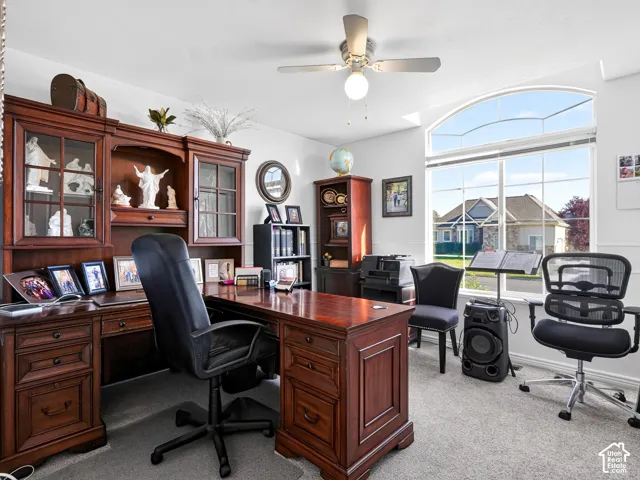 Arch-top window with multi-pane design, neutral-toned carpeting, and a ceiling fan with integrated lighting