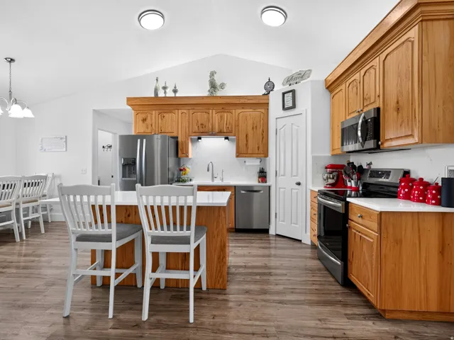 Kitchen featuring wood-finish cabinetry, stainless steel appliances, white countertops, and wood-finish flooring