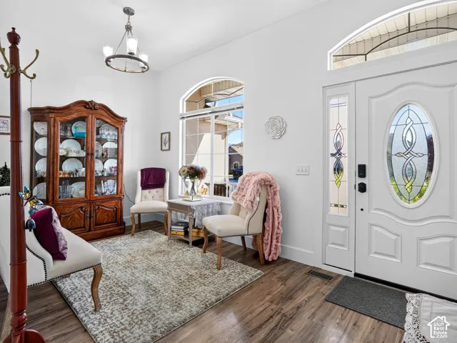 Wood-finish flooring throughout, bright white walls, and a decorative front door with leaded glass details