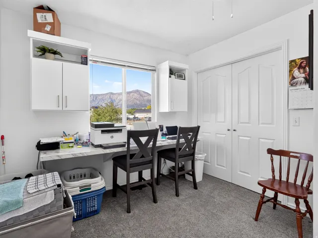Built-in desk with a white marble-finish countertop, dual upper white cabinetry, and carpet flooring