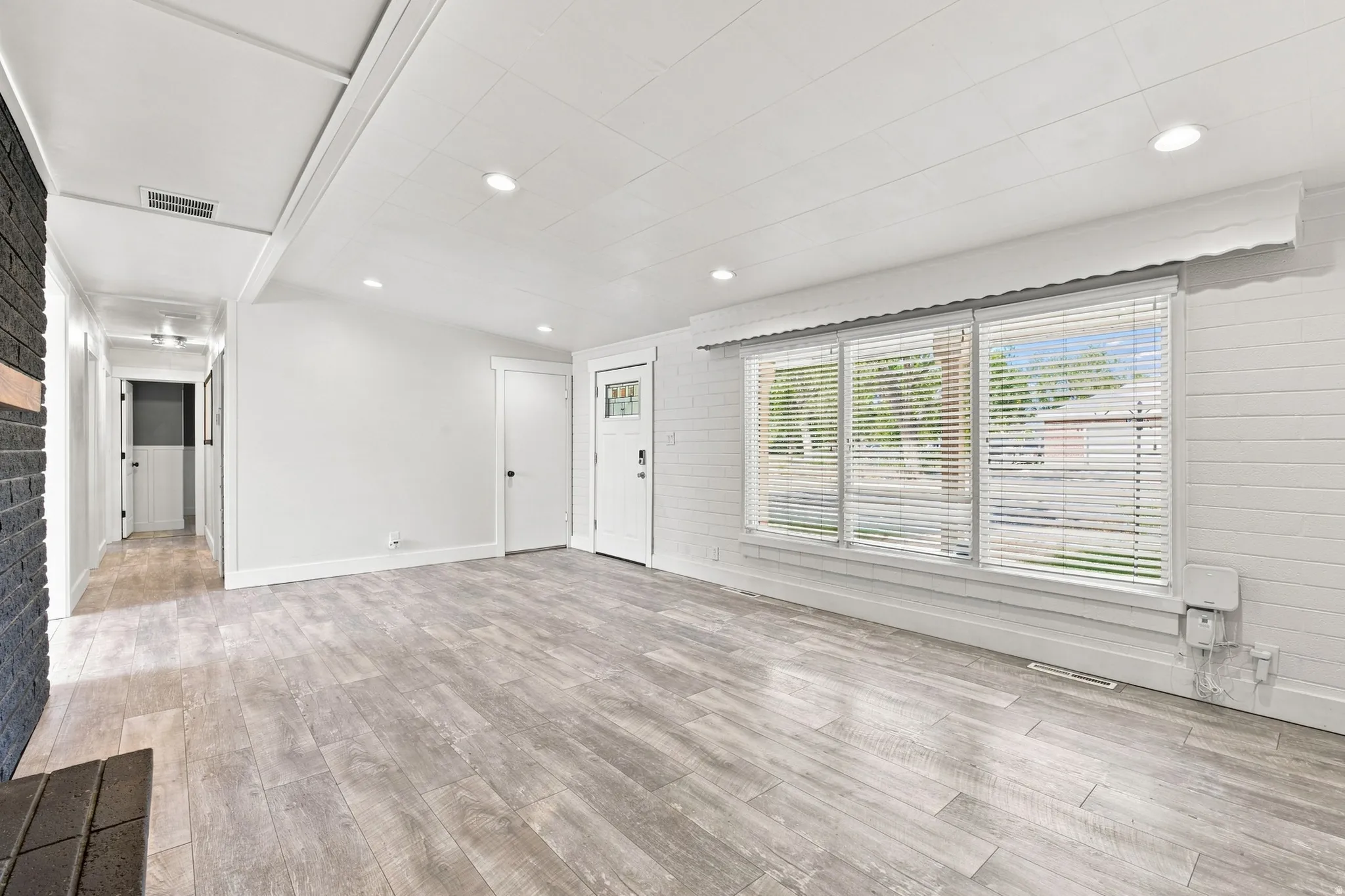 Wood-finish flooring throughout, recessed lighting, and a front entry door with decorative glass inserts