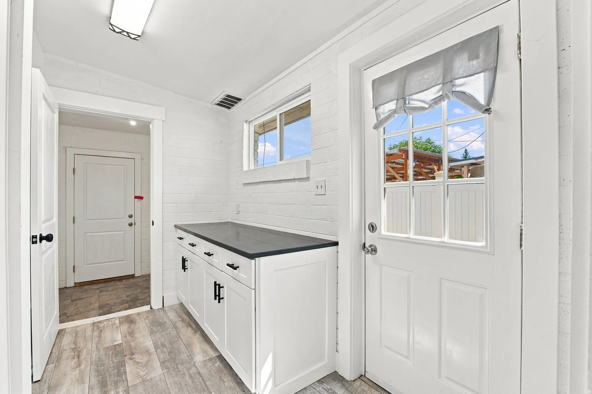 Extra cabinetry with pull out drawers, dark countertop, and wood-finish flooring