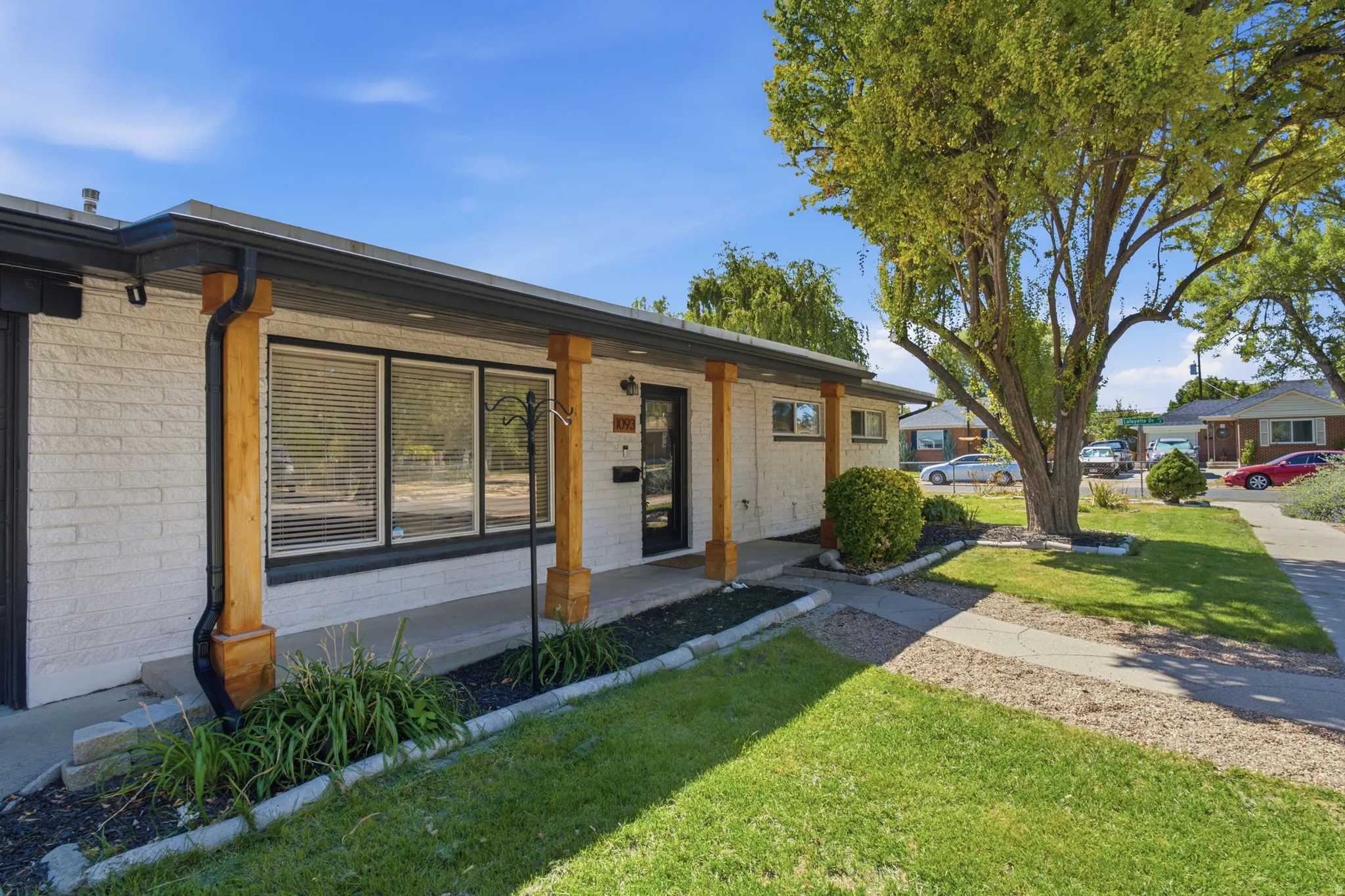 White brick exterior with natural wood-tone pillars and contrasting dark trim
