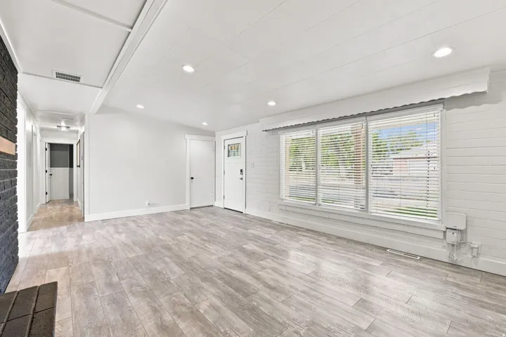 Wood-finish flooring throughout, recessed lighting, and a front entry door with decorative glass inserts