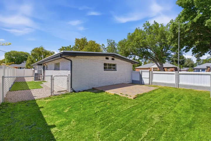 Expansive lawn area, paver patio, chain-link fencing, privacy fencing, and a white brick exterior