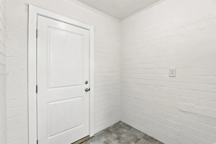 White painted brick walls and a two-panel interior door with brushed nickel hardware