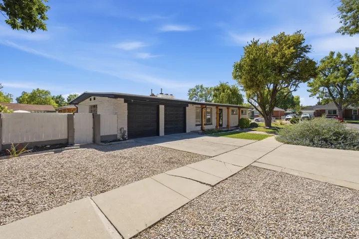 White brick exterior with a flat roofline, two-car garage with black doors, covered front entry with wood columns, and a concrete driveway