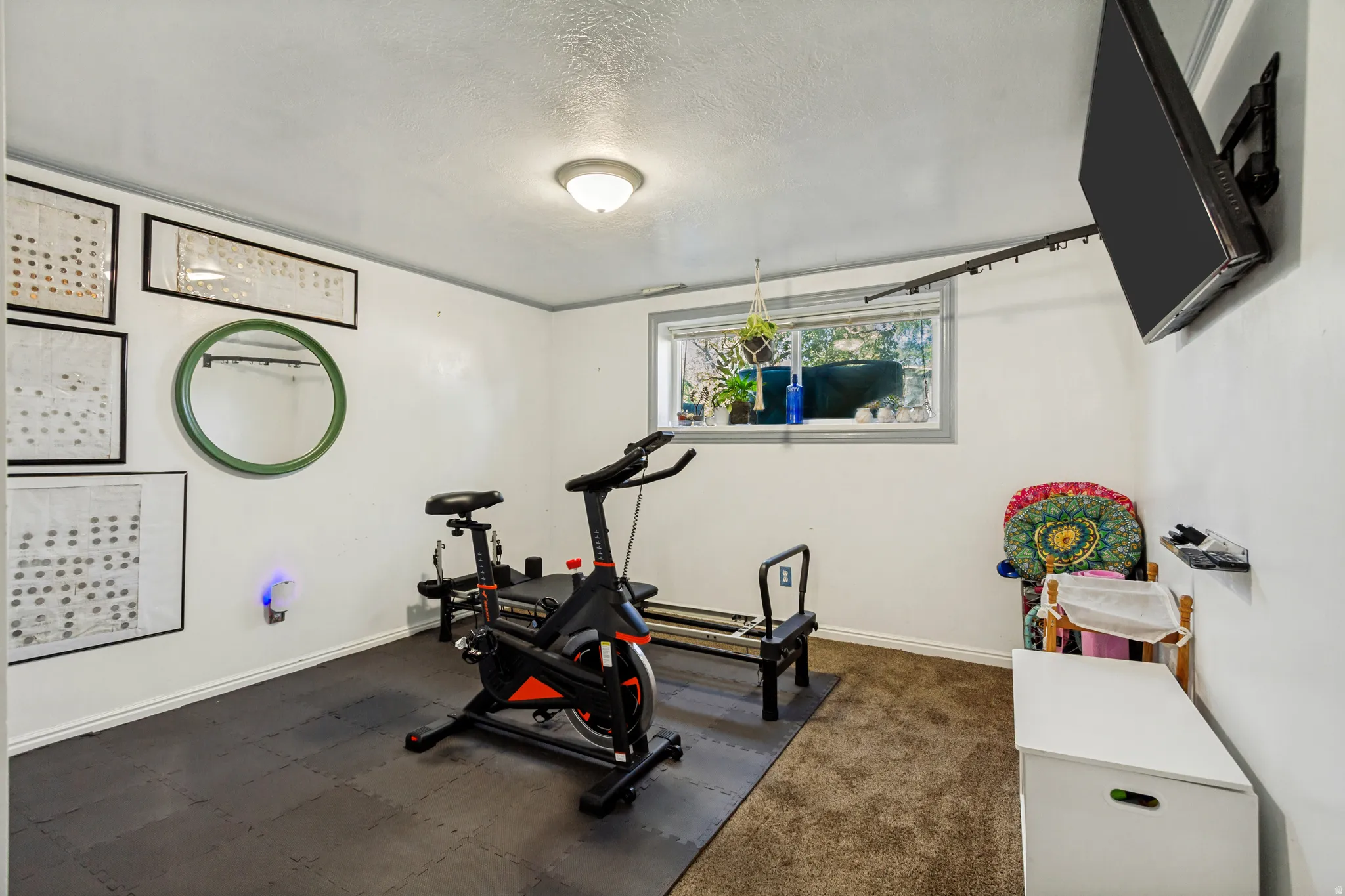 Recessed window with exterior visibility, ceiling-mounted lighting, wall-mounted television bracket, a combination of carpet and interlocking floor tiles