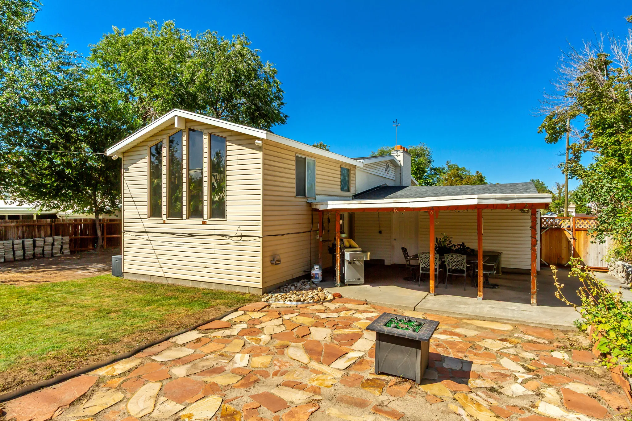 Exterior featuring large arched window, covered patio, flagstone patio, and a fire pit