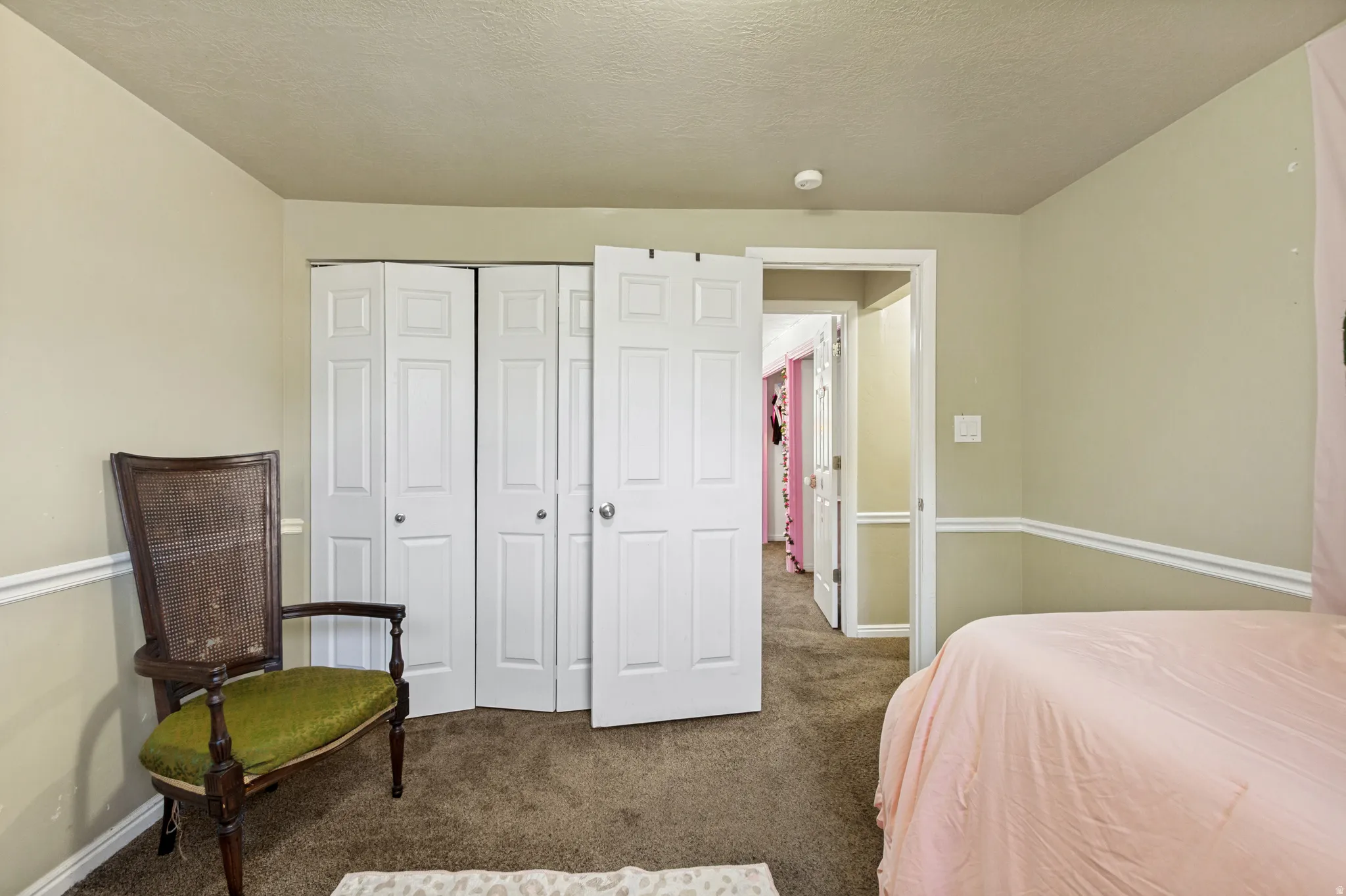 Carpeted flooring, bi-fold closet doors, and painted walls with chair rail molding