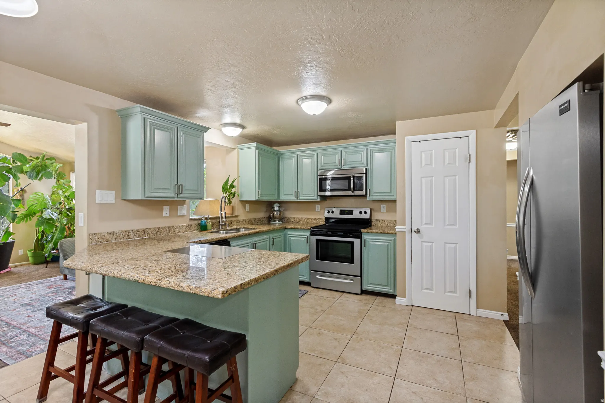 Kitchen featuring light blue cabinetry, granite countertops, tile flooring, and stainless steel appliances