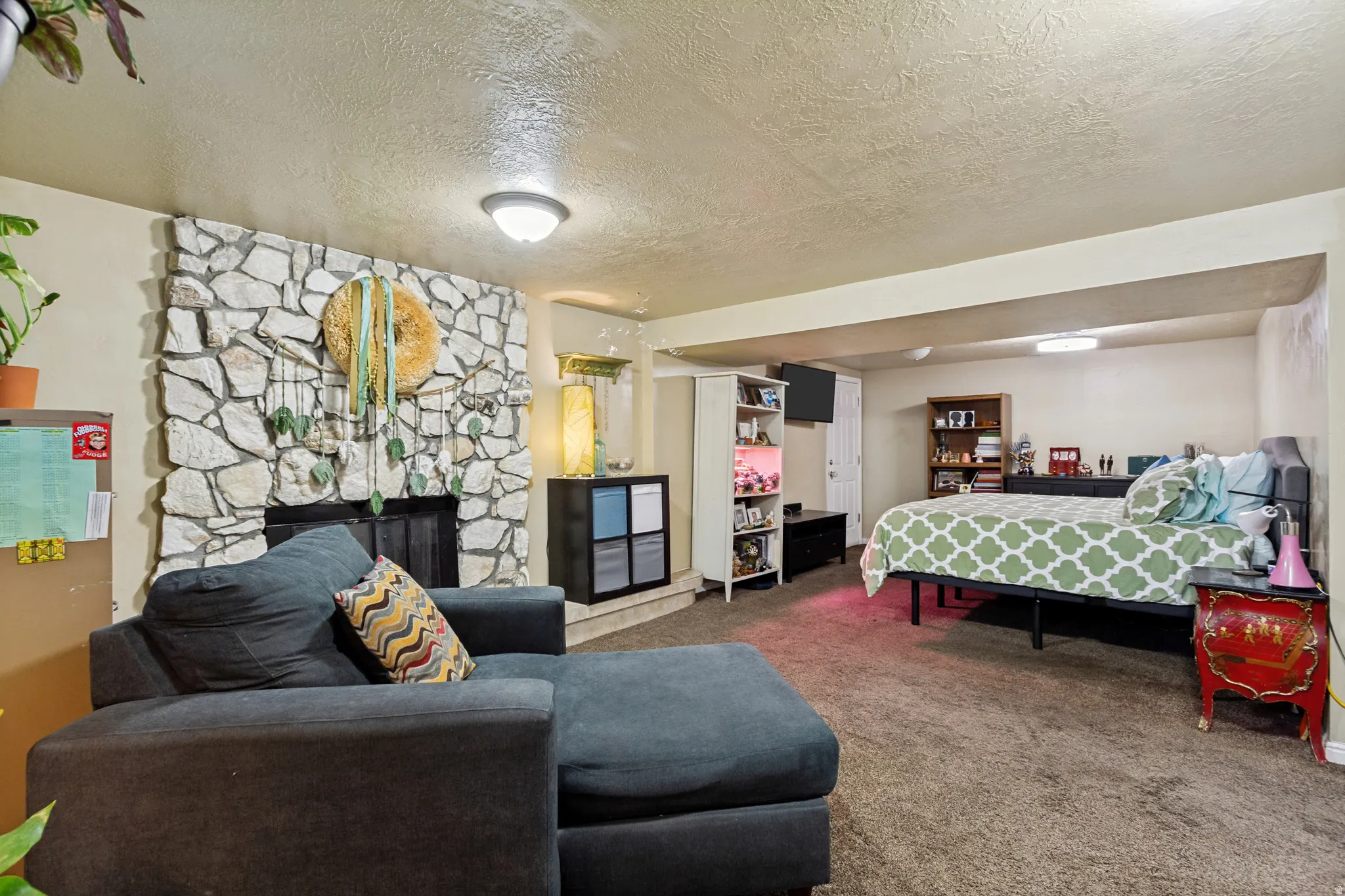 Stone-clad fireplace with a dark-toned hearth, wall-to-wall carpeting, and recessed lighting