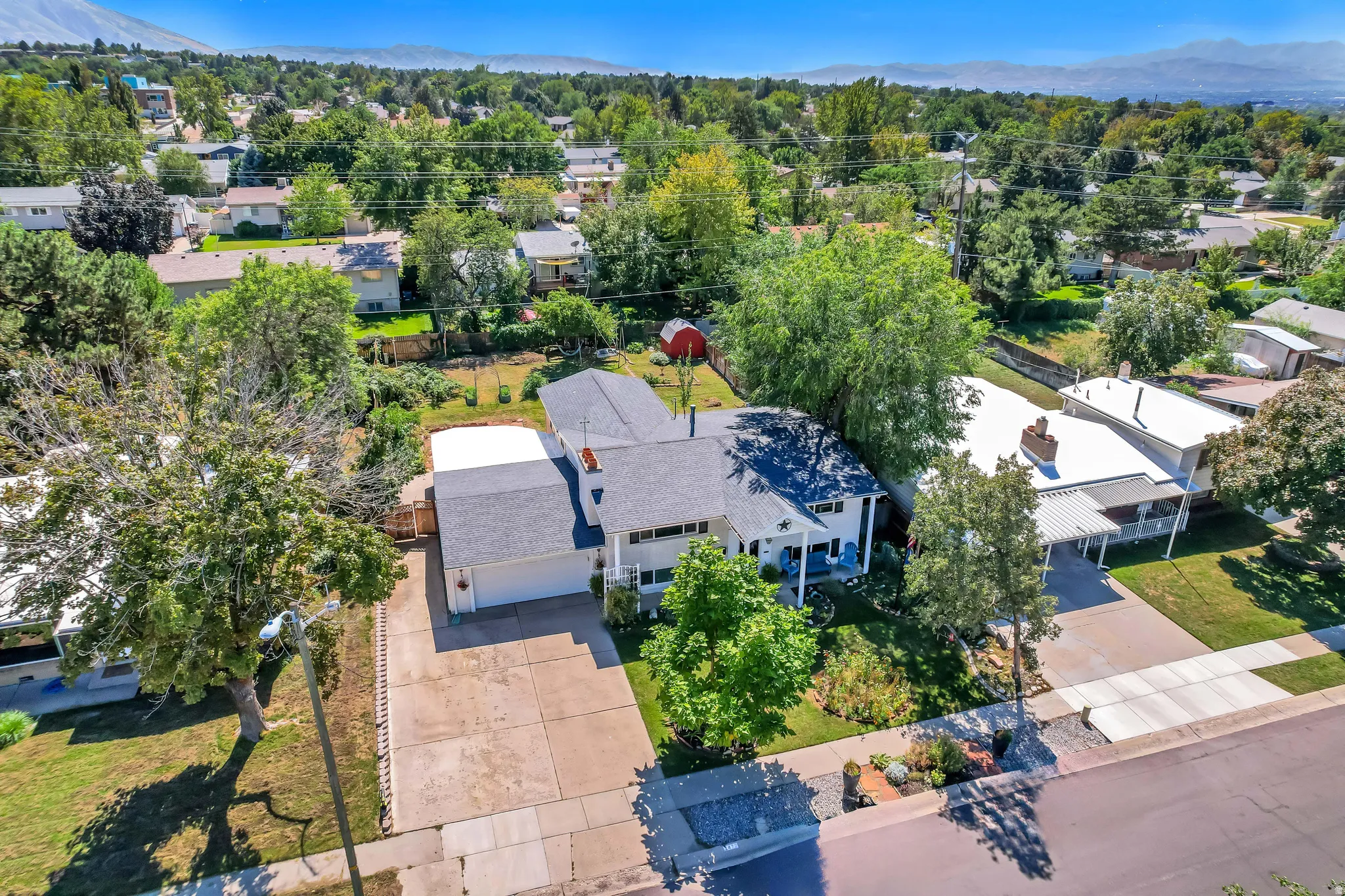 Expansive property featuring a two-story residence with a garage, mature trees, and a paved driveway