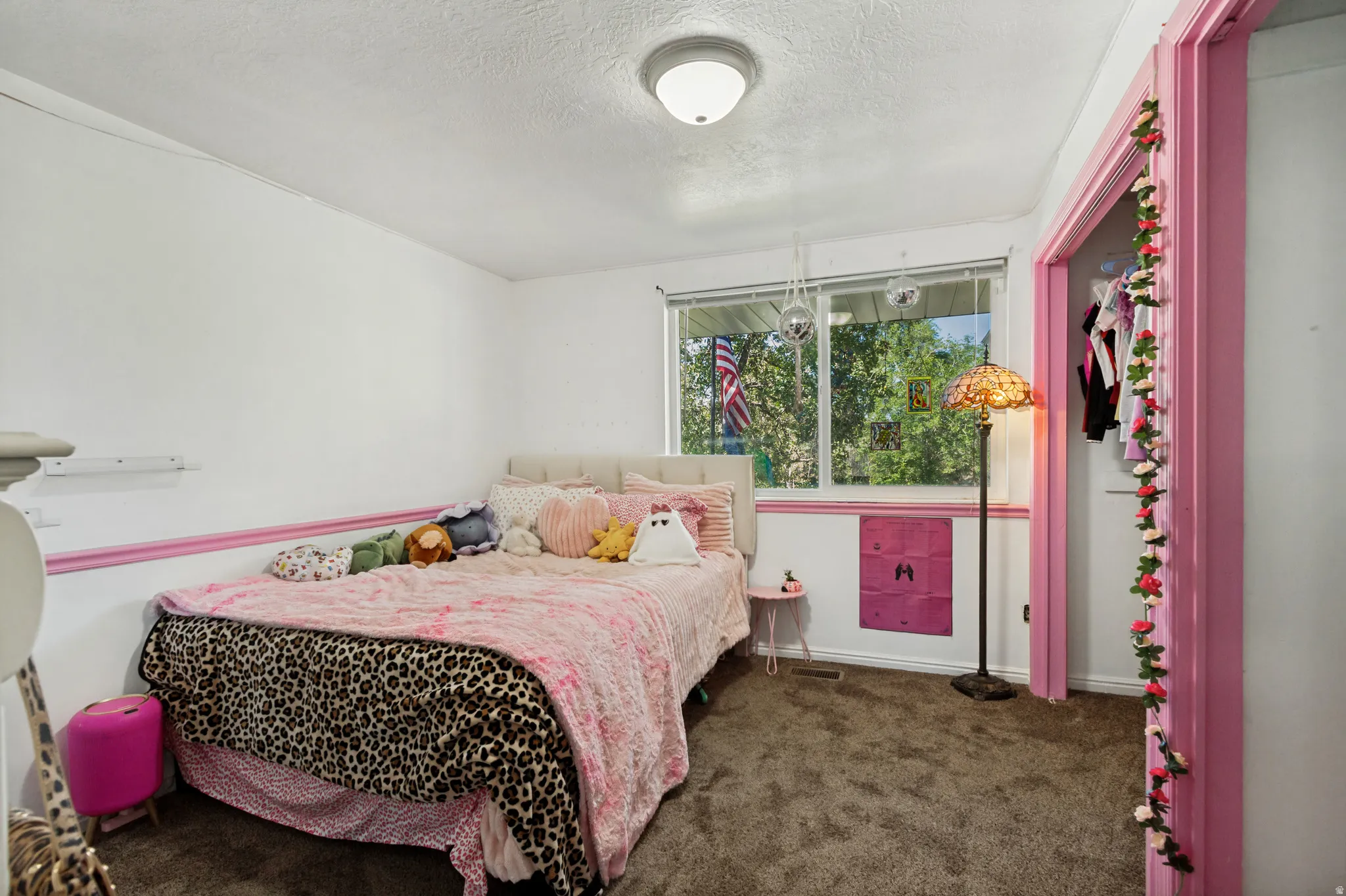 White walls with pink trim, carpeted flooring, and a large window
