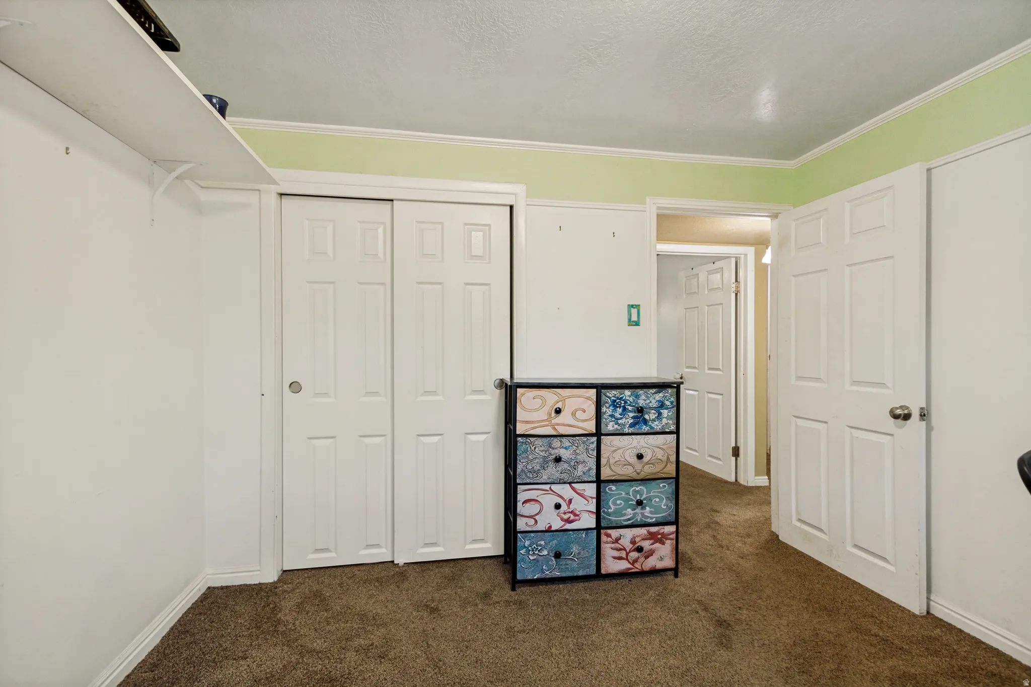 Carpeted flooring with white trim and a contrasting green accent wall