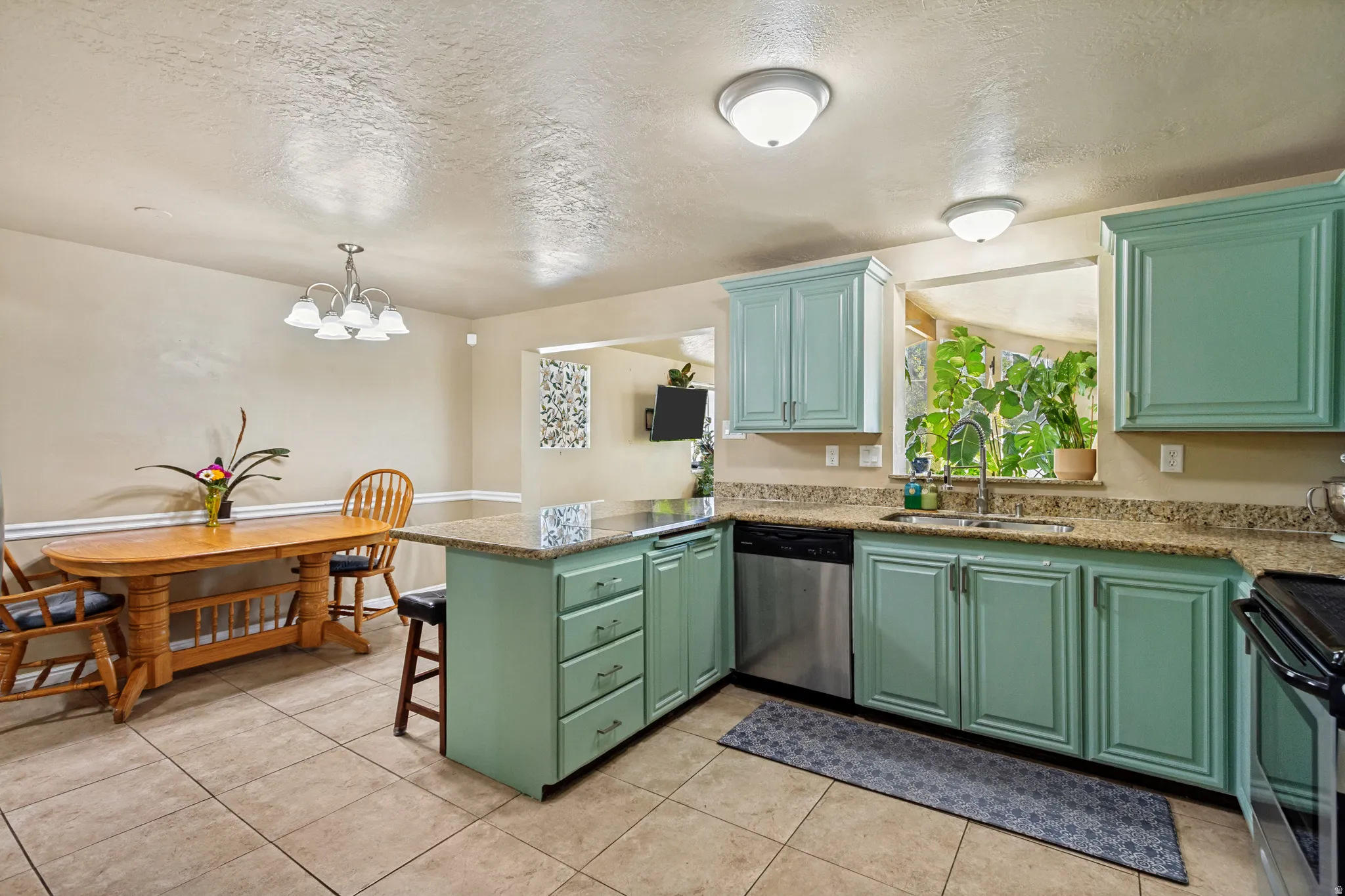Kitchen featuring sage cabinetry, granite countertops, stainless steel appliances, and tile flooring