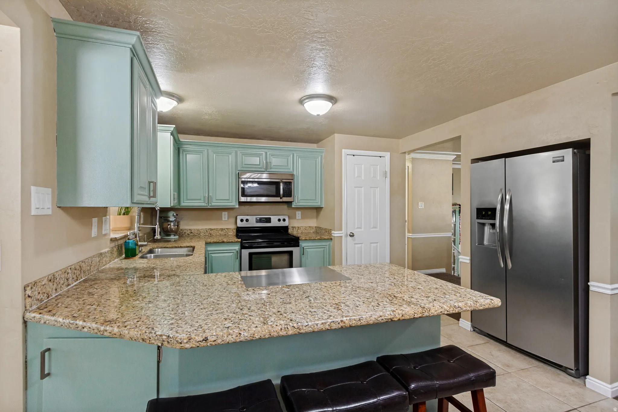 Kitchen featuring light blue cabinetry, granite countertops, stainless steel appliances, and tile flooring