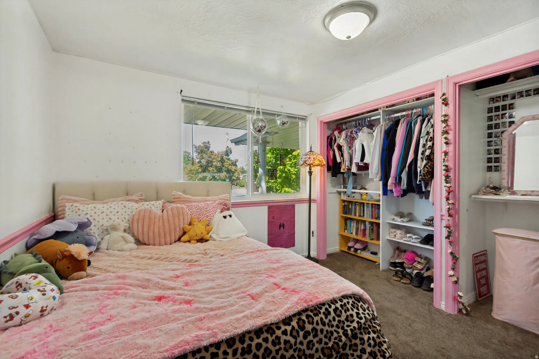 Window with outdoor scenery, recessed closet shelving, built-in closet organization, neutral wall color, ceiling-mounted light fixture
