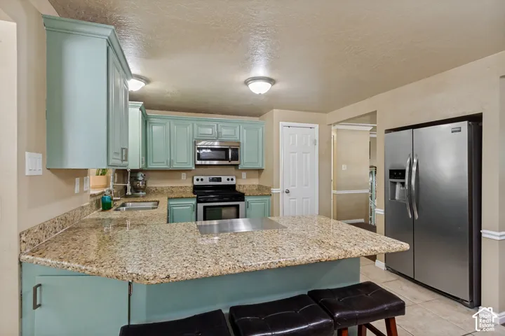 Kitchen featuring light blue cabinetry, granite countertops, stainless steel appliances, and tile flooring