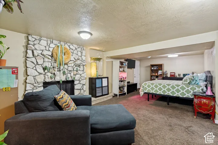 Stone-clad fireplace with a dark-toned hearth, wall-to-wall carpeting, and recessed lighting
