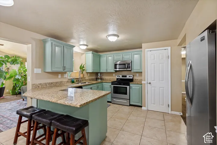 Kitchen featuring light blue cabinetry, granite countertops, tile flooring, and stainless steel appliances