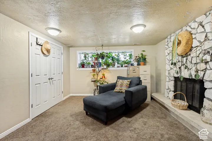 Finished basement recreation room featuring neutral carpet flooring, recessed ceiling lighting, a decorative fireplace with stone surround, and a high transom window with natural light