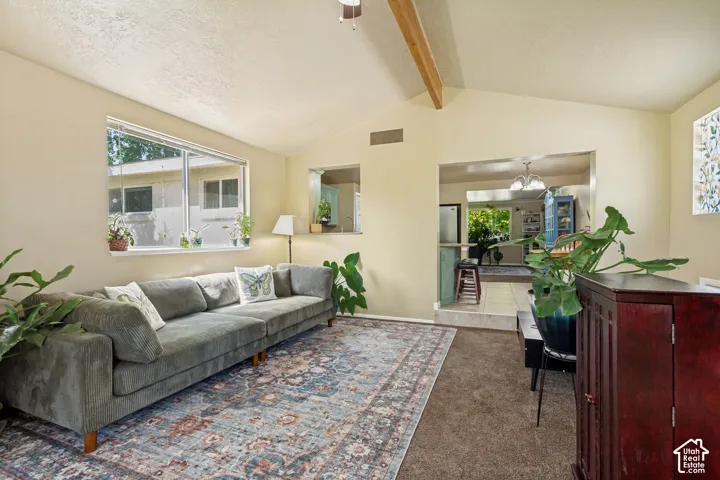 Vaulted ceiling with exposed wood beams, large windows, and a cased opening