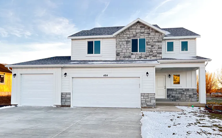Two-story exterior with white siding and stone accents, featuring a three-car garage and covered front entry