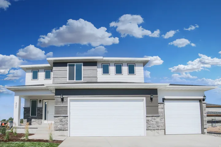 Modern exterior featuring multi-textured siding, stone veneer accents, an attached multi-car garage, and a covered entry
