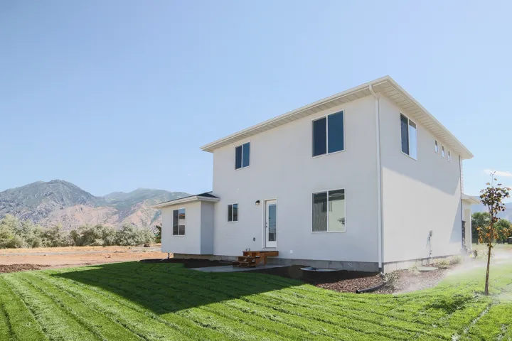 Two-story residence with a stucco exterior, multiple windows, and a glass-paneled door