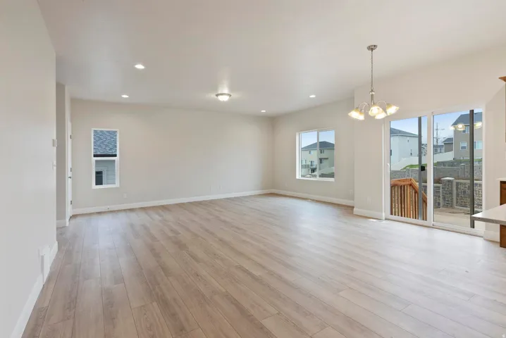Open-concept living area with wood-finish flooring, recessed lighting, a sliding glass door, and multiple windows providing natural illumination