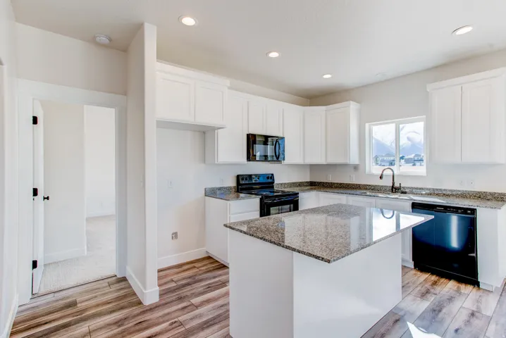 Kitchen featuring white shaker cabinetry, granite countertops, a central island, recessed lighting, and wood-finish flooring