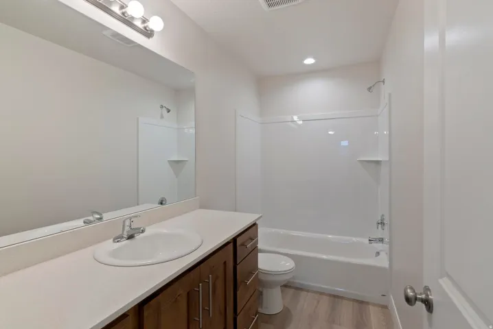Vanity with an integrated sink, broad mirror, and wood-finish cabinetry