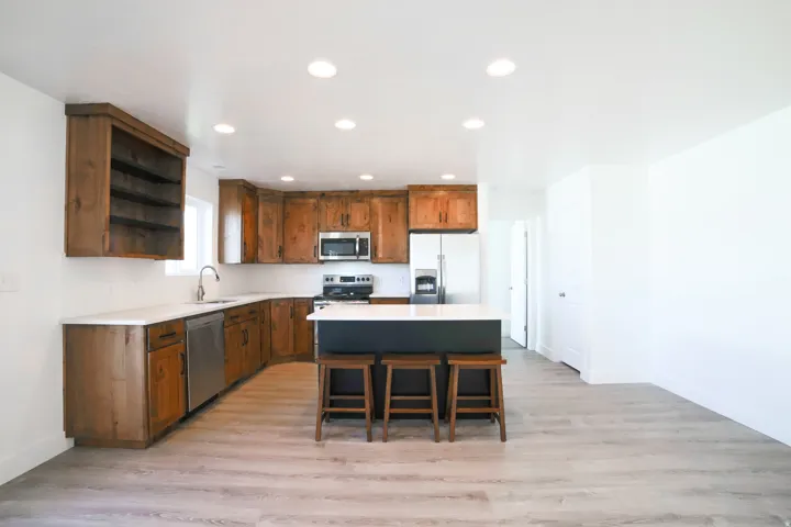 Kitchen featuring wood cabinetry, white countertops, stainless steel appliances, and a central island