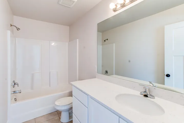 White vanity with integrated sink, chrome faucet, and expansive wall-mounted mirror