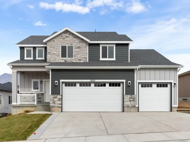 Two-story home with a stone and siding exterior, featuring a covered entry porch, a three-car garage, and a concrete driveway