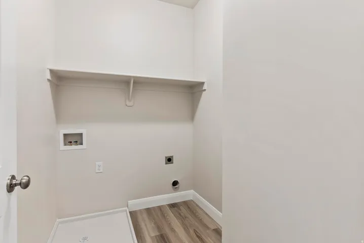 Utility area featuring wood-finish flooring, a wall-mounted shelf, and appliance hookups