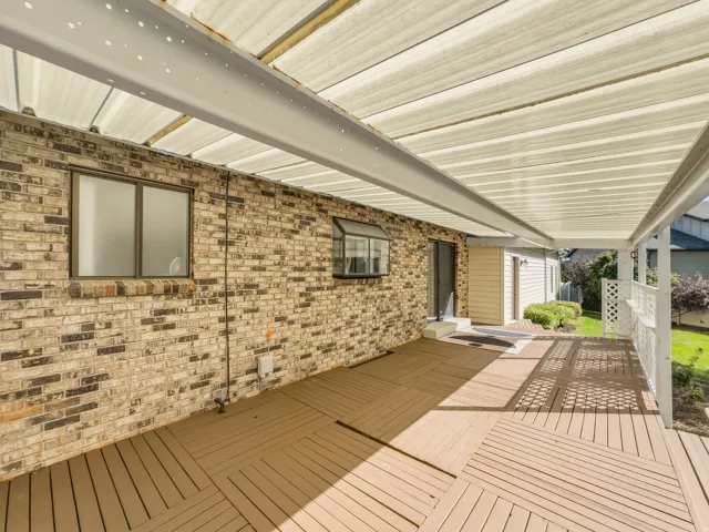 Covered patio featuring a slatted roof, wood-finish decking, and brick exterior