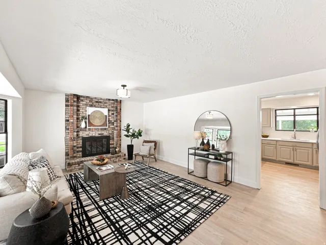 Brick-front fireplace, wood-finish flooring, recessed lighting, and kitchen entry
