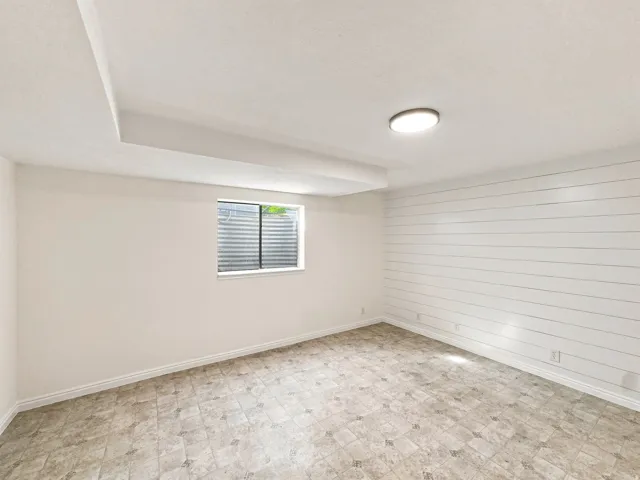 Recessed ceiling features, overhead lighting, window with horizontal blinds, shiplap accent wall, and patterned tile flooring