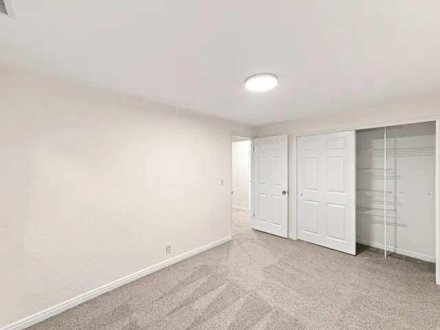 Neutral tone wall finishes, flush mount ceiling lighting, and soft carpet flooring