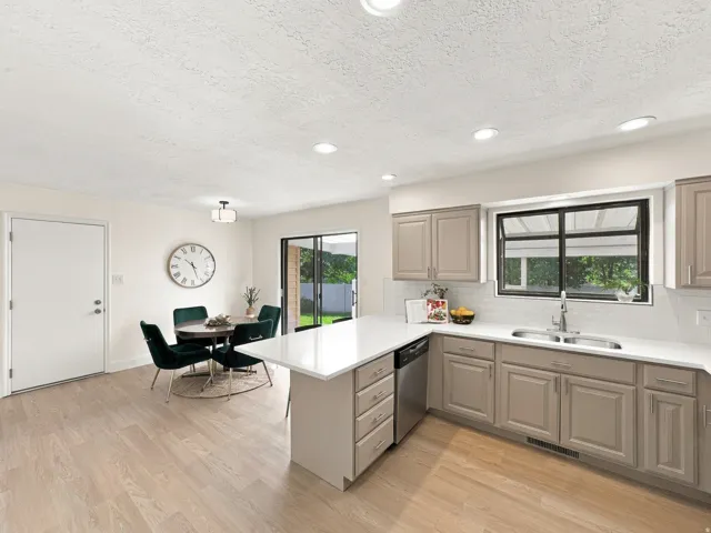 Light wood-finish flooring, recessed lighting, gray cabinetry, stainless steel dishwasher, and white countertops