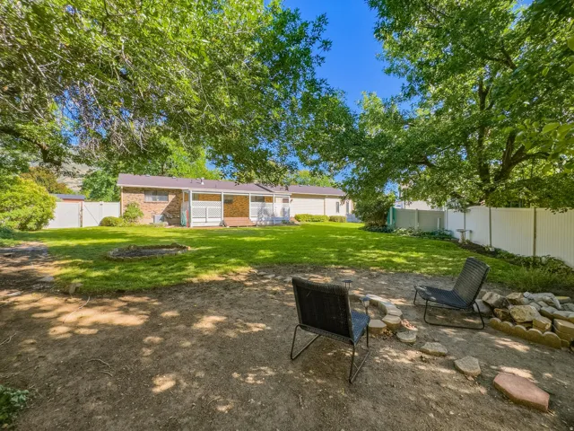 Expansive yard featuring a manicured lawn, mature trees, and a brick exterior dwelling