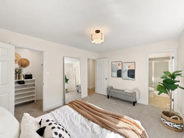 Carpeted bedroom with a built-in closet, a ceiling-mounted light fixture, and an attached bathroom featuring a shower with a glass enclosure