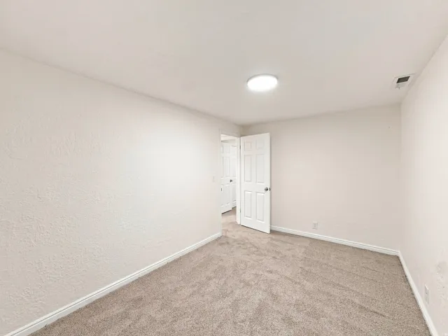 Neutral-toned carpeting, white baseboards, and a flush-mount ceiling light