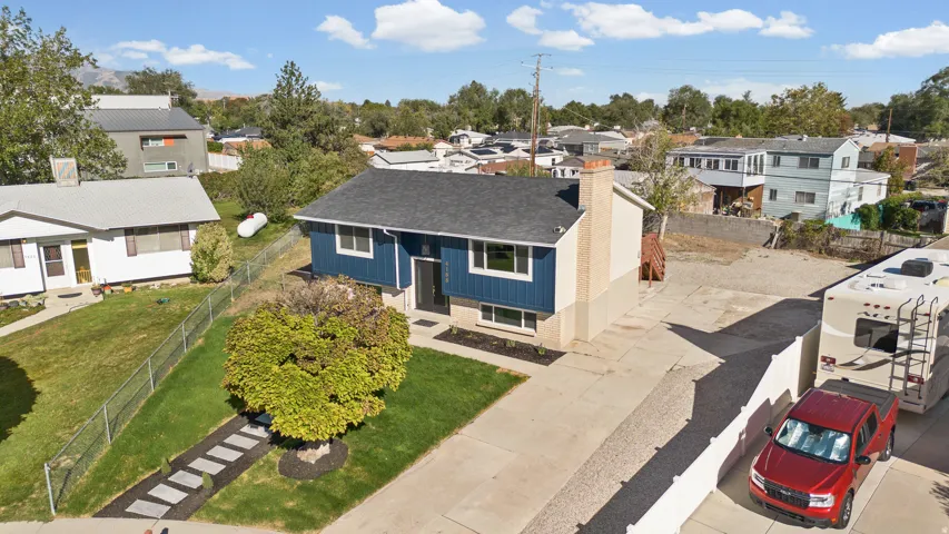 Two-story residence featuring blue siding with white trim, a dark shingled roof, a paved driveway, and a front lawn with a stone pathway